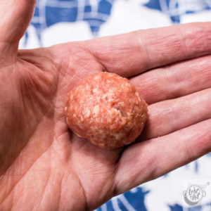 Meatball rolled into shape setting in a hand.