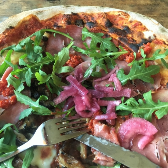 Homemade pizza topped with ham, arugala and pickled onions. Homemade pizza topped with ham, arugala and pickled onions.